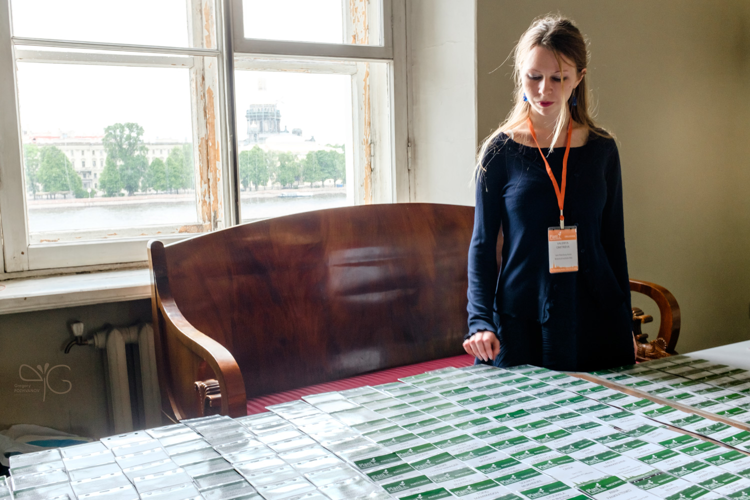 Valeria Dmitrieva stands behind a registration desk filled with participant badges